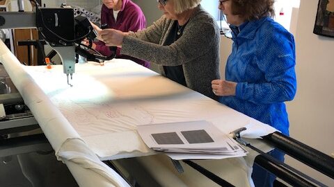 3 women learning to use a longarm quilting machine at Burlington Electric Quilters